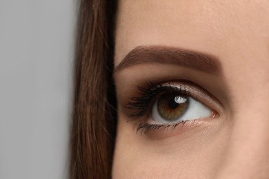 Photo of Young woman with beautiful eyes on grey background, closeup view
