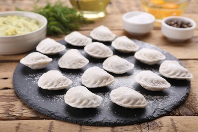 Photo of Raw dumplings (varenyky) and ingredients on wooden table