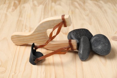 Slingshot with stones on wooden table, closeup