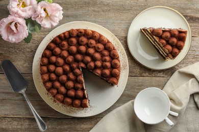 Delicious tiramisu cake and flowers on wooden table, flat lay