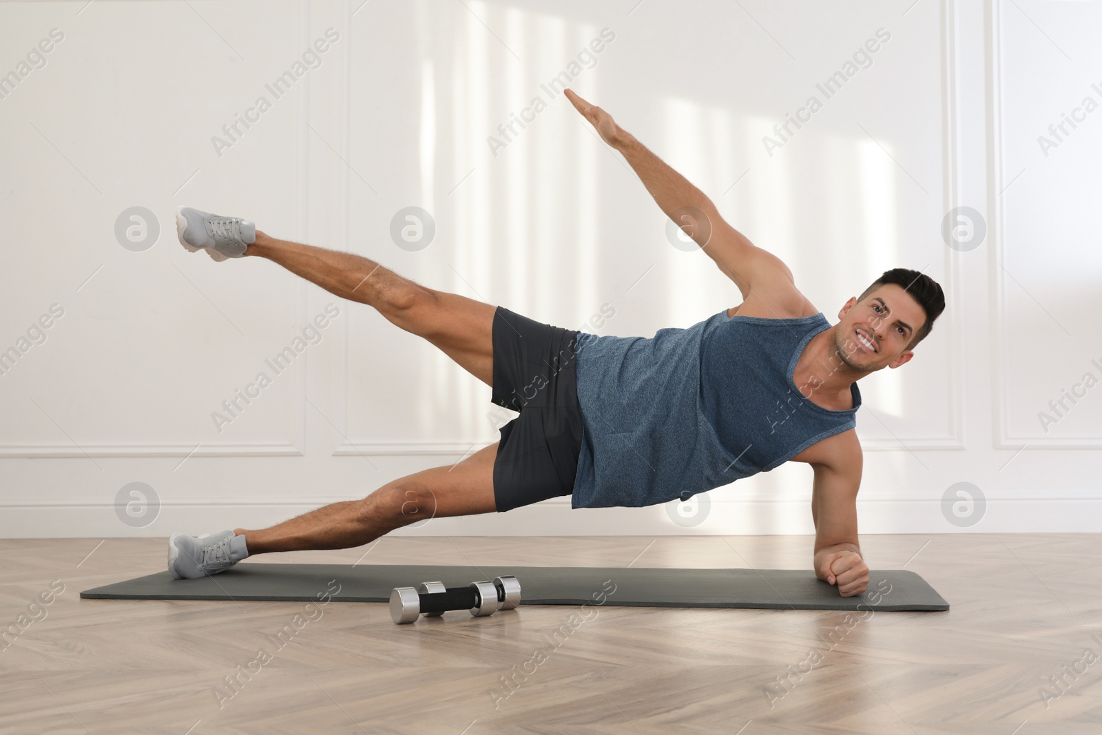 Photo of Handsome man doing exercise on yoga mat indoors