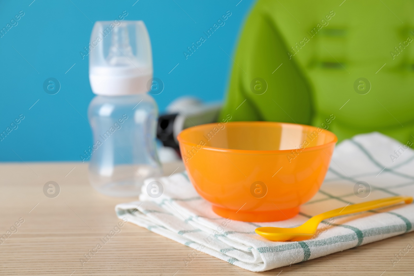 Photo of Set of plastic dishware on wooden table. Serving baby food