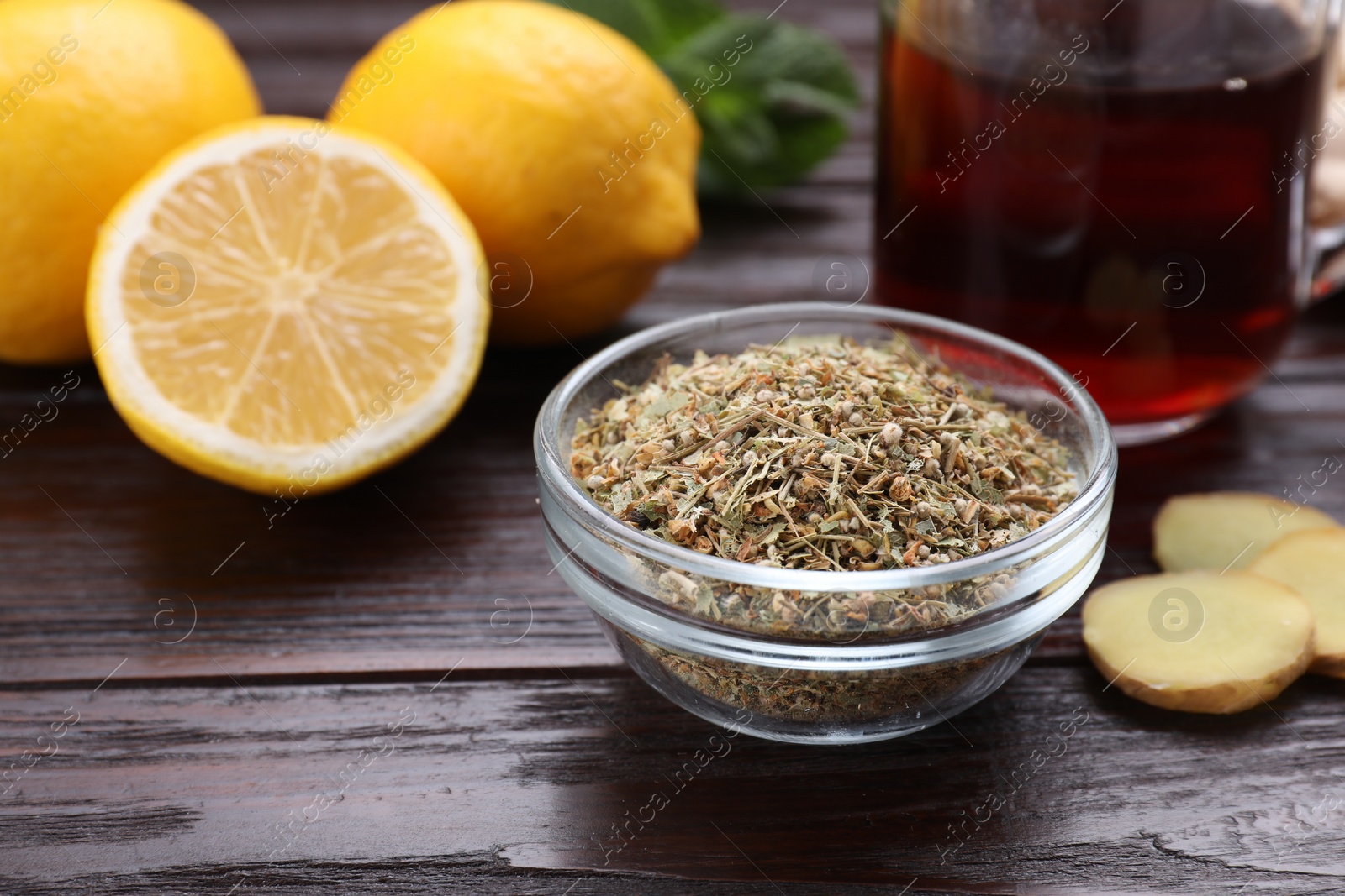Photo of Glass bowl of dry tea and lemon on wooden table, closeup with space for text. Natural cough remedies