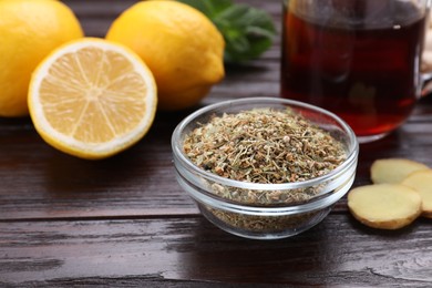 Glass bowl of dry tea and lemon on wooden table, closeup with space for text. Natural cough remedies