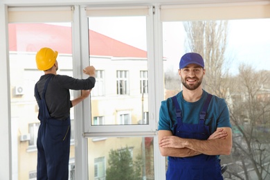 Construction workers installing plastic window in house