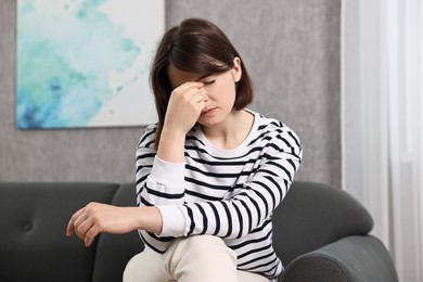 Photo of Overwhelmed woman sitting on sofa at home