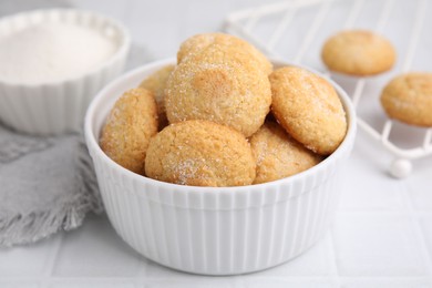 Photo of Tasty sugar cookies in bowl on white tiled table, closeup