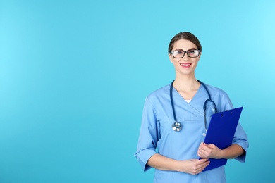 Photo of Young medical student with clipboard on color background. Space for text