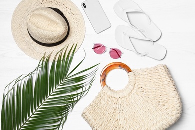 Flat lay composition with beach bag and accessories on white wooden background