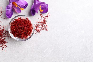 Photo of Dried saffron and crocus flowers on grey table, flat lay. Space for text