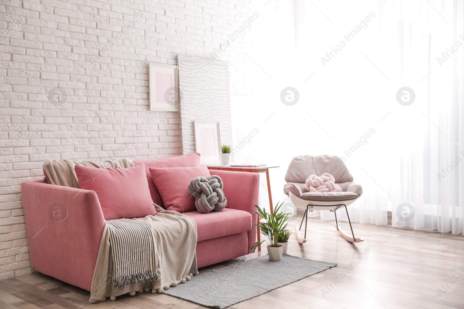 Photo of Stylish living room interior with sofa and rocking armchair near brick wall. Space for text