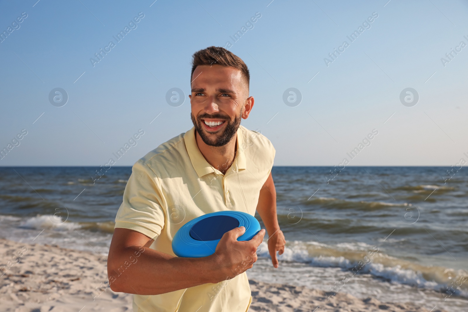 Photo of Happy man throwing flying disk at beach on sunny day