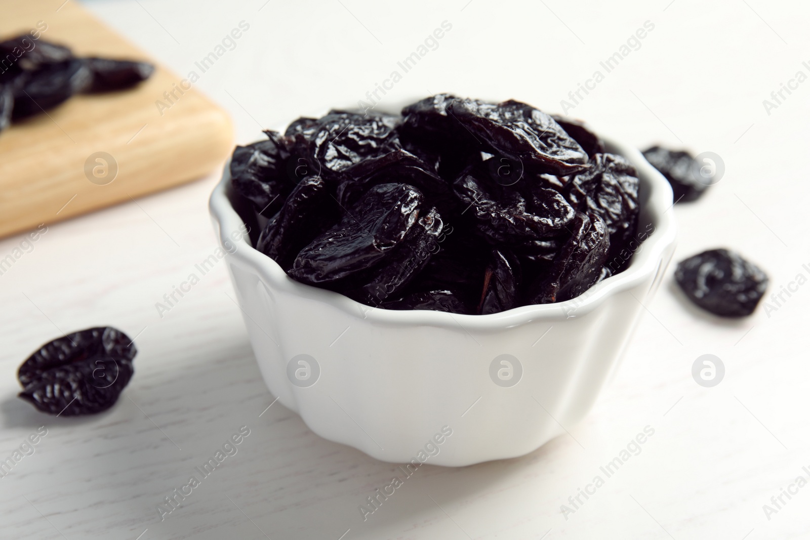 Photo of Bowl of sweet dried plums on table, closeup. Healthy fruit