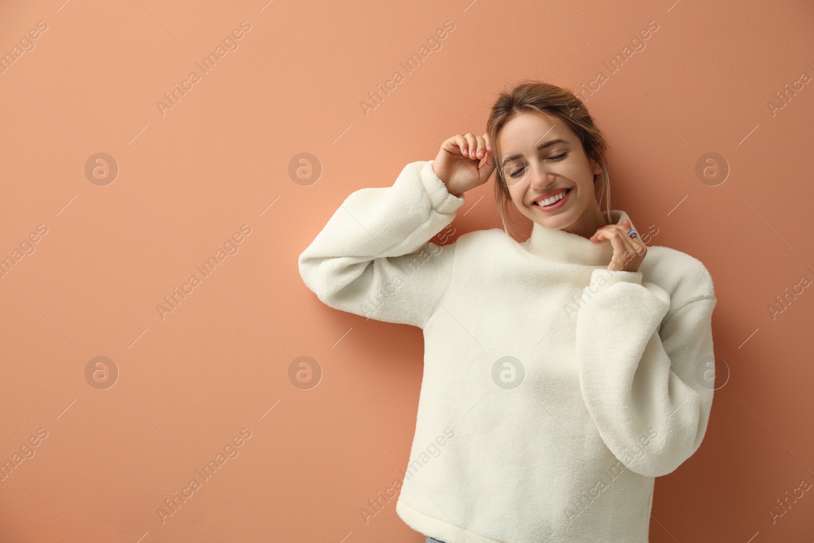 Photo of Beautiful young woman wearing knitted sweater on light brown background. Space for text