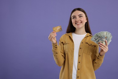 Happy woman with credit card and dollar banknotes on purple background, space for text