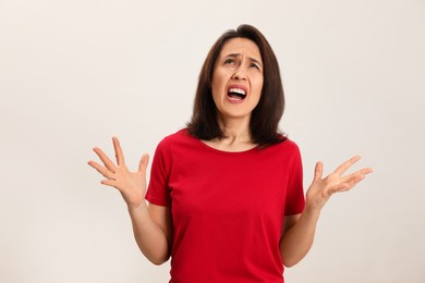 Portrait of screaming woman filled with hate on light background