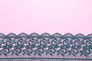 Photo of Green lace on pink background, top view. Space for text