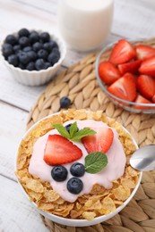 Delicious crispy cornflakes, yogurt and fresh berries in bowl on white wooden table. Healthy breakfast