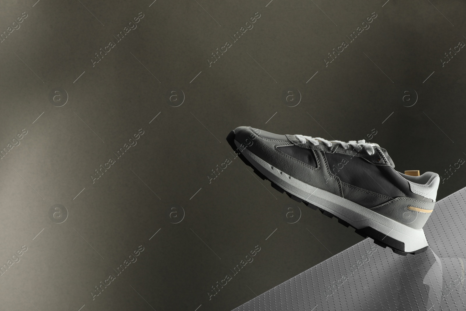 Photo of Stylish presentation of trendy sneaker against grey background, space for text