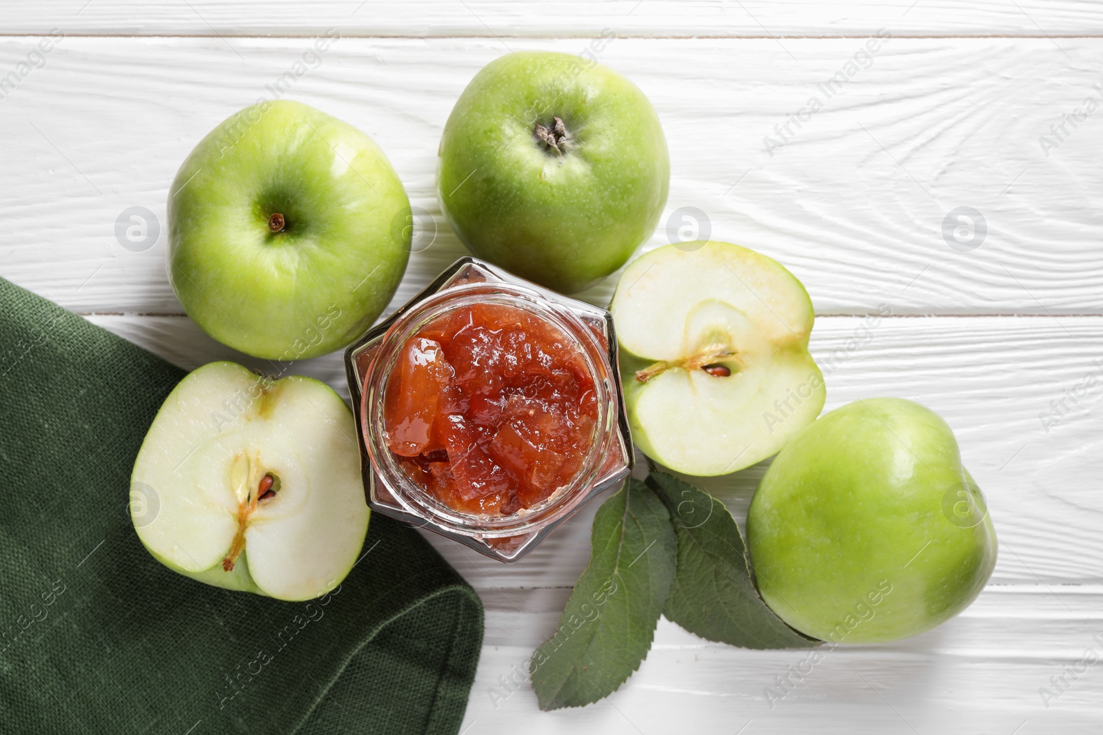 Photo of Glass jar of delicious apple jam and fresh fruits on white wooden table, flat lay