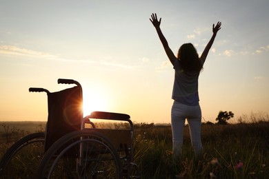 Woman standing near wheelchair in evening outdoors, back view. Healing miracle