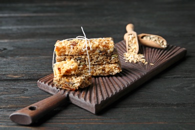 Photo of Wooden board with cereal bars on table. Whole grain snack