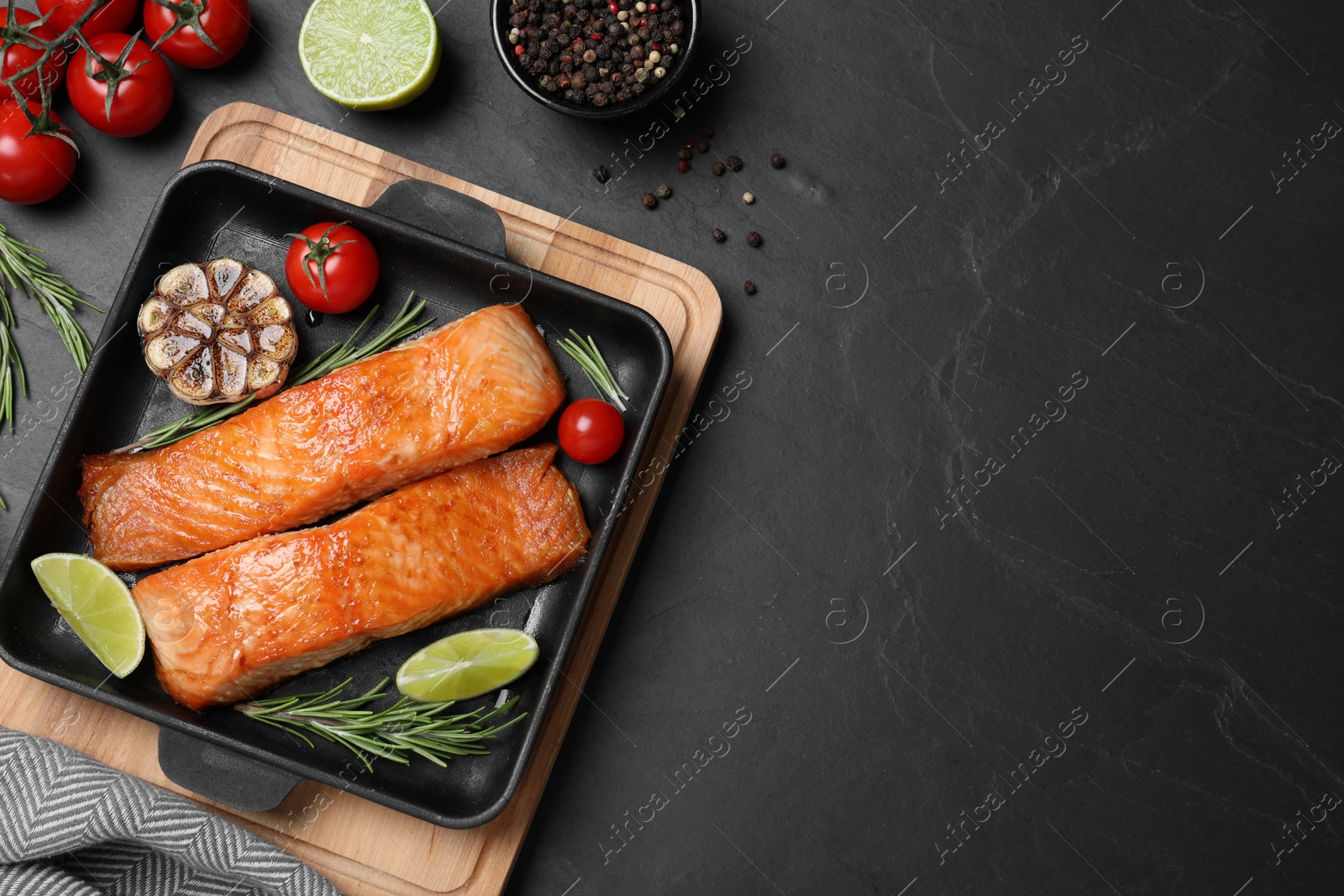 Photo of Delicious roasted fish served on black table, flat lay. Space for text