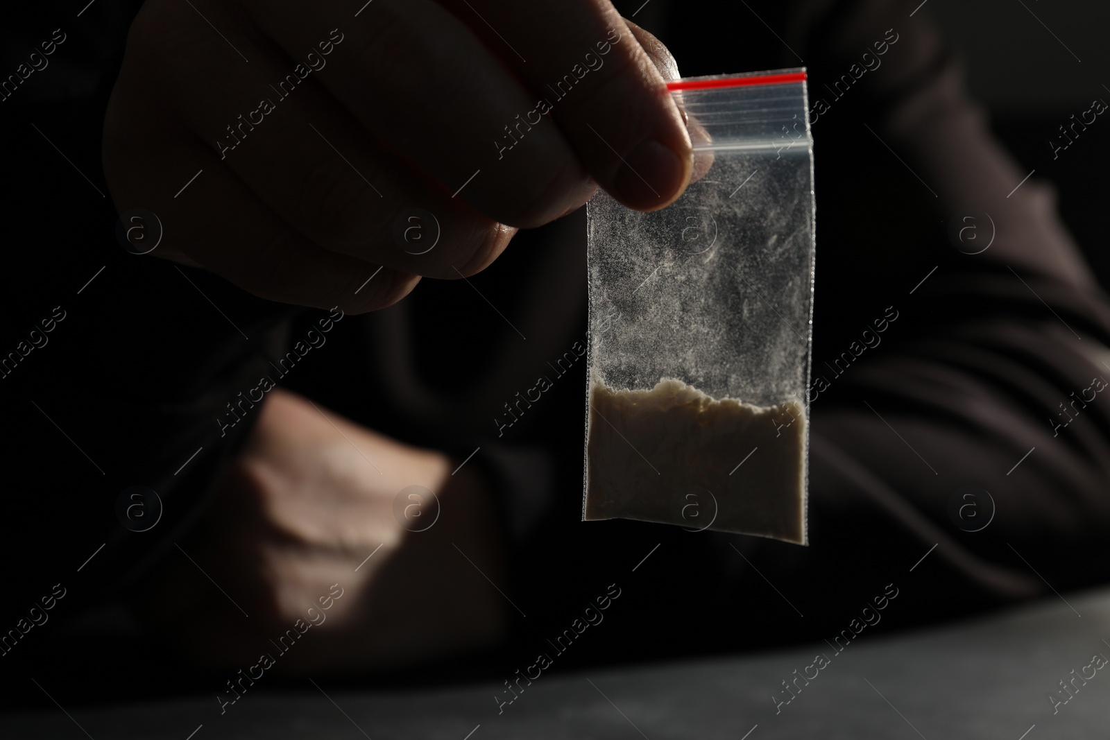 Photo of Drug addiction. Man with plastic bag of cocaine at grey table, selective focus