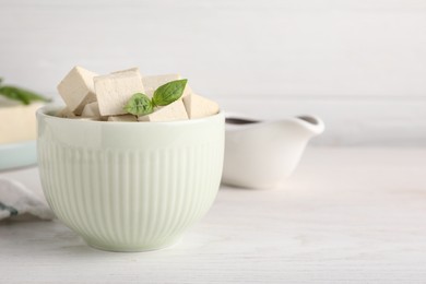 Delicious tofu with basil on white wooden table. Space for text