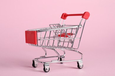 Small metal shopping cart on pink background