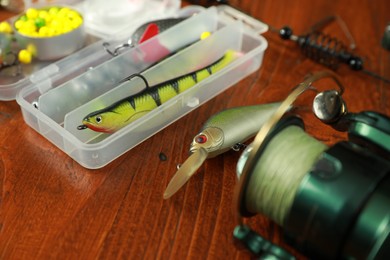 Fishing tackle. Spinning reel, lures and bait on wooden table, closeup