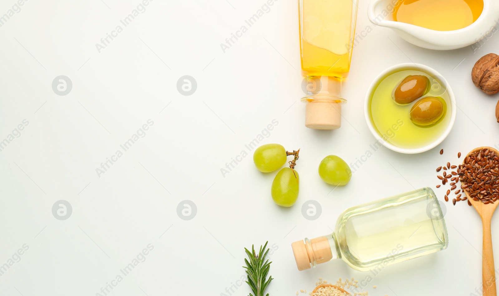 Photo of Vegetable fats. Different oils in glass bottles and ingredients on white table, flat lay. Space for text