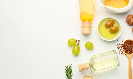 Vegetable fats. Different oils in glass bottles and ingredients on white table, flat lay. Space for text