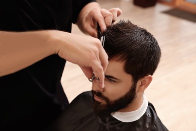 Photo of Professional hairdresser working with client in barbershop, closeup