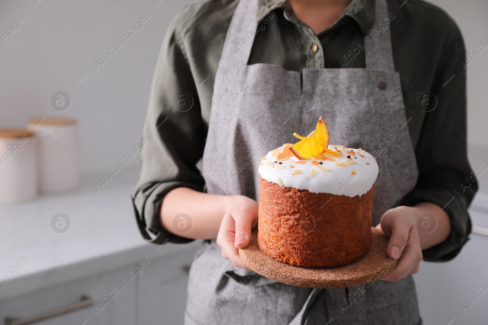 Photo of Young woman with traditional decorated Easter cake in kitchen, closeup. Space for text