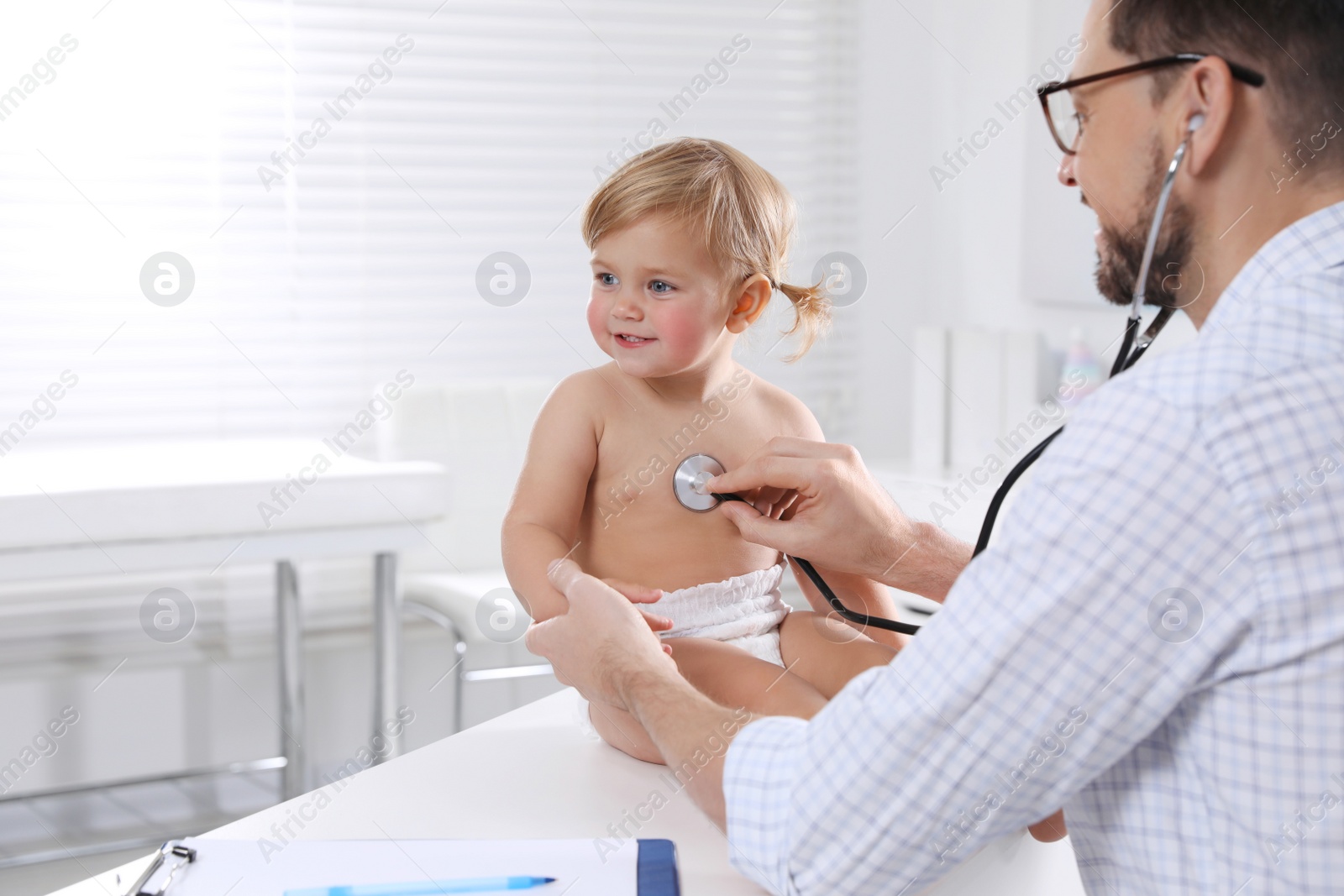 Photo of Pediatrician examining baby with stethoscope in clinic