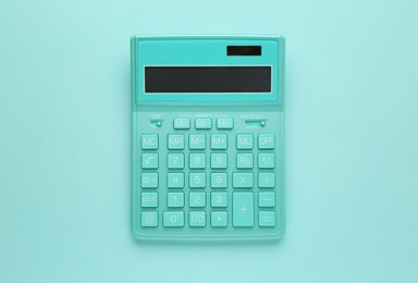 Turquoise calculator on light blue background, top view