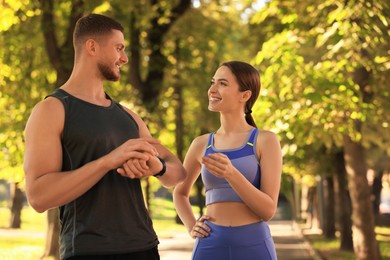 Photo of Attractive happy couple checking pulse after training in park on sunny day