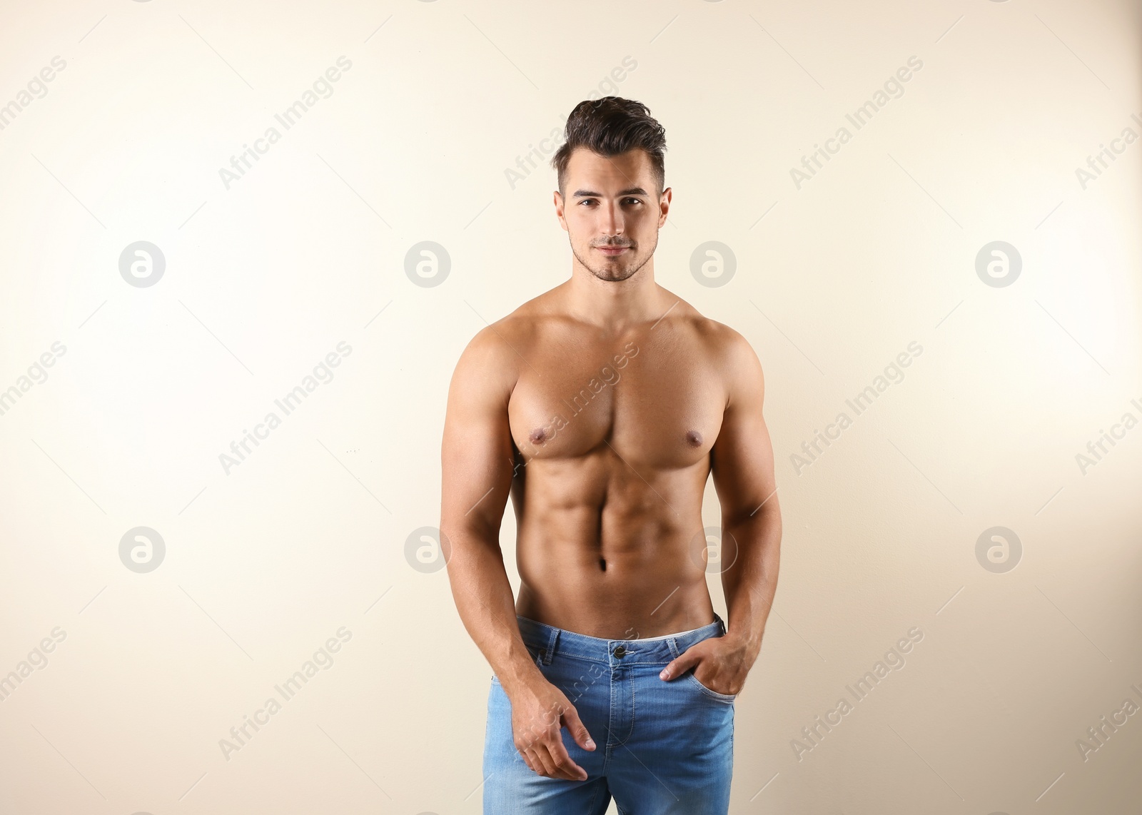 Photo of Shirtless young man in stylish jeans on light background