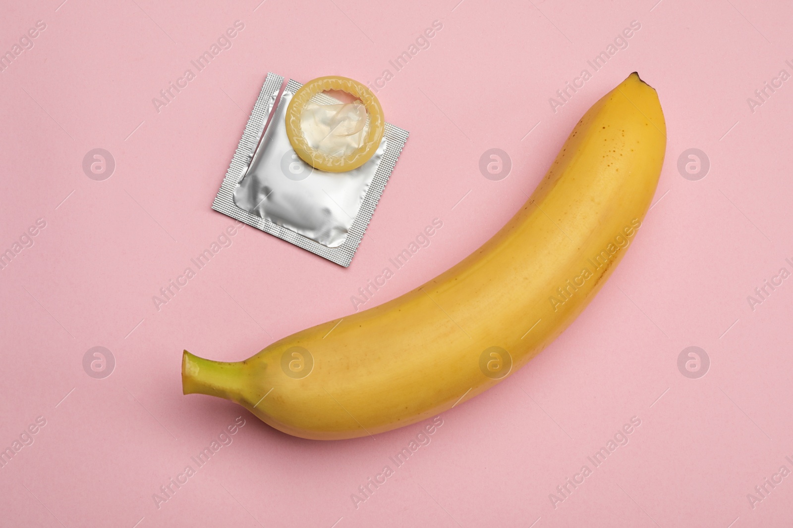 Photo of Condom and banana on pink background, flat lay. Safe sex