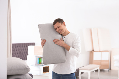 Happy man with cushion in mattress store