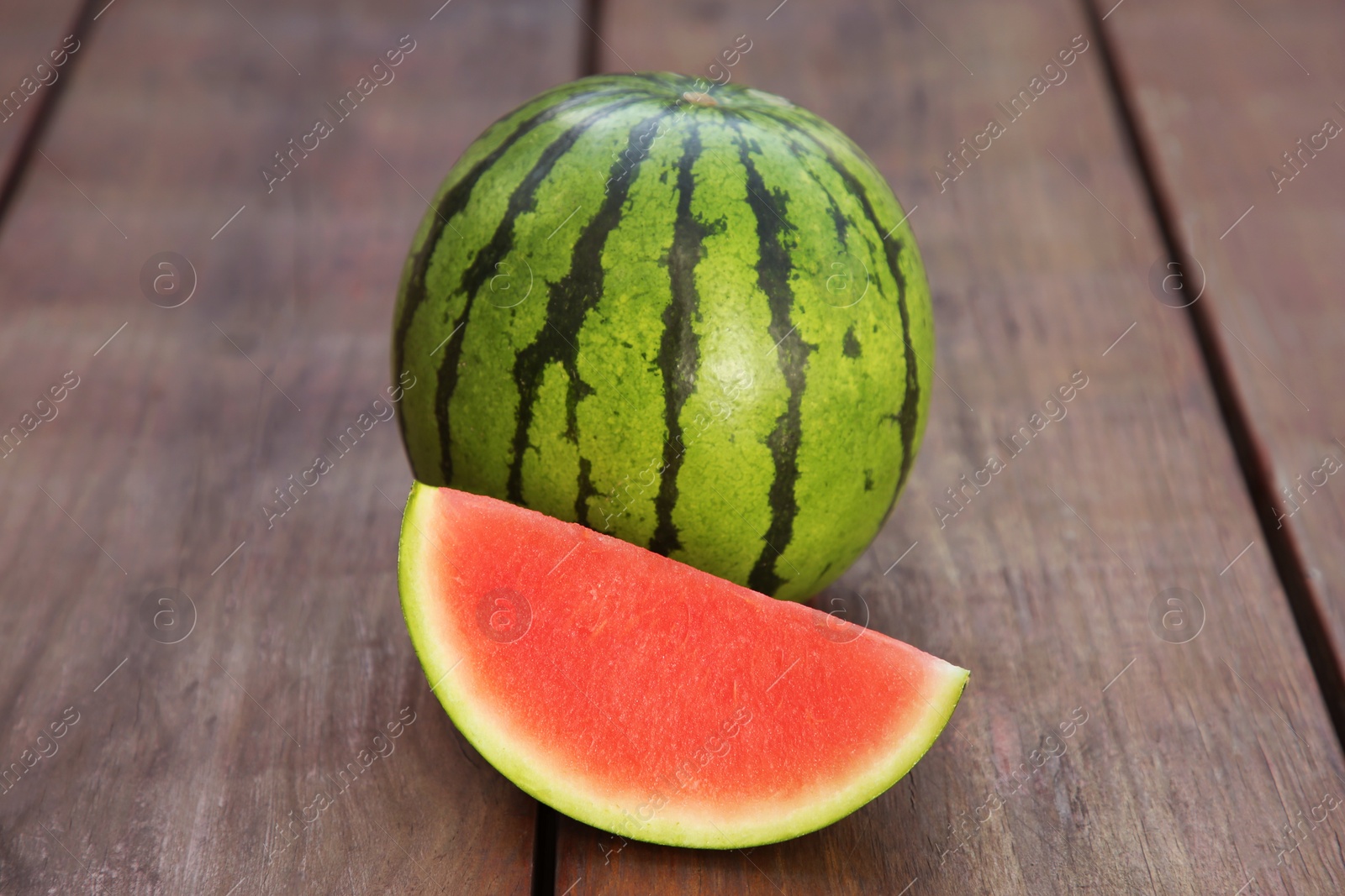 Photo of Whole and cut delicious ripe watermelons on wooden table