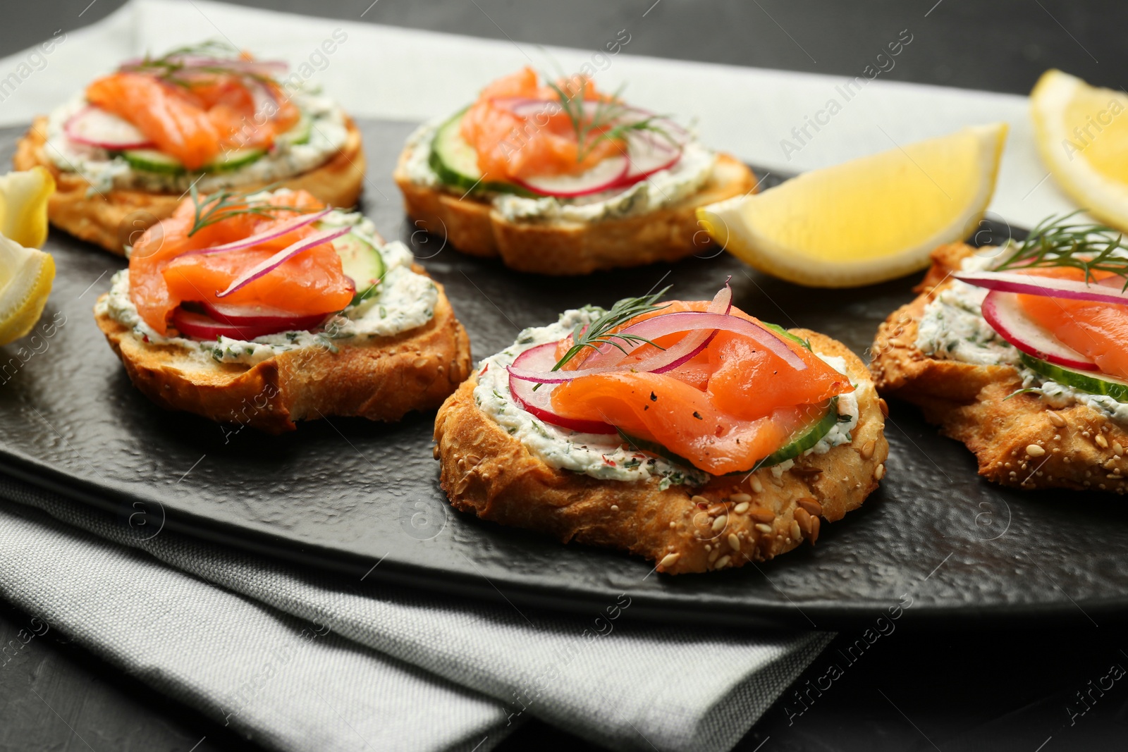 Photo of Tasty canapes with salmon, cucumber, radish and cream cheese on table, closeup