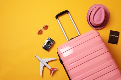 Photo of Flat lay composition with suitcase and travel accessories on yellow background. Summer vacation