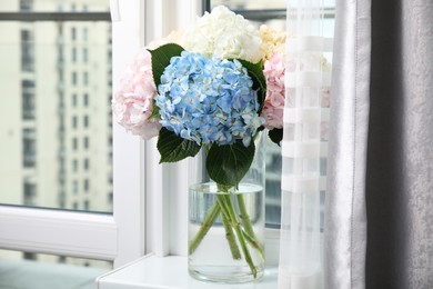 Photo of Beautiful hydrangea flowers in vase on windowsill indoors