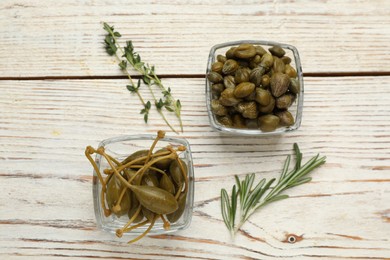 Tasty capers, rosemary and thyme on white wooden table, flat lay