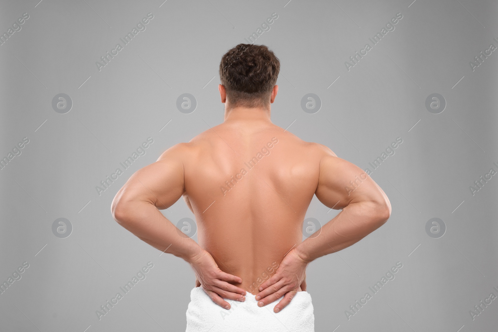 Photo of Man suffering from back pain on grey background, back view