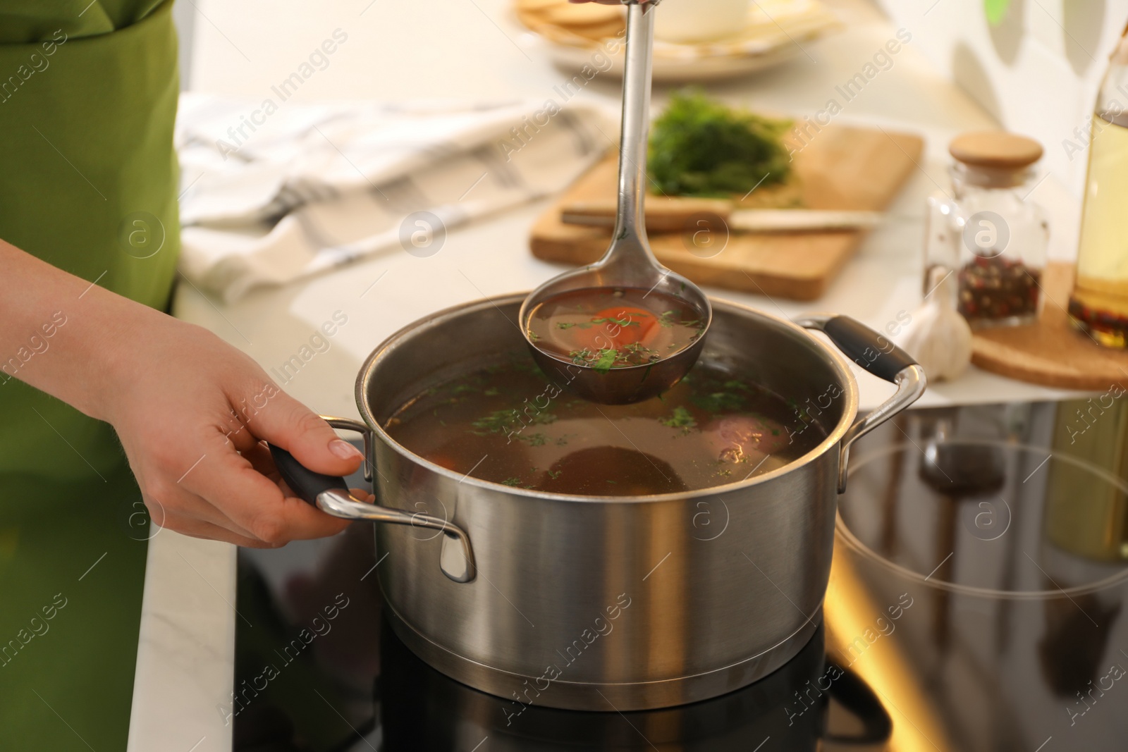 Photo of Woman making bouillon on stove in kitchen, closeup. Homemade recipe