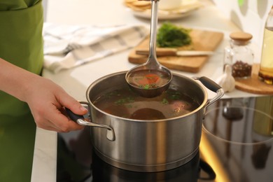 Woman making bouillon on stove in kitchen, closeup. Homemade recipe