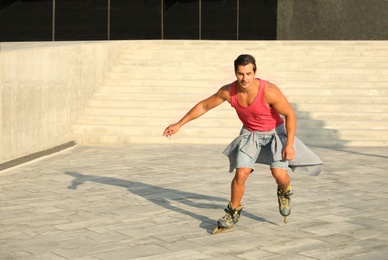 Photo of Handsome young man roller skating on city street, space for text
